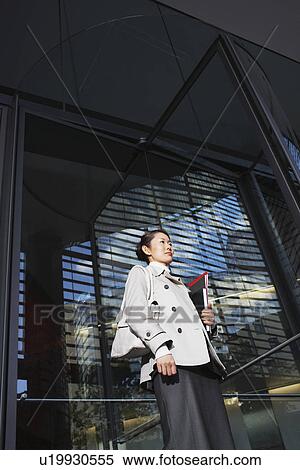 Stock Photography - Woman Carrying Notebooks, standing outside, low angle view. Fotosearch