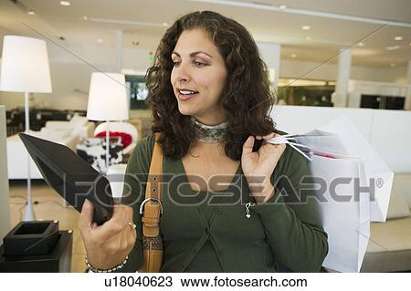Stock Image - Woman Examining Bowl in furniture store, close up. Fotosearch