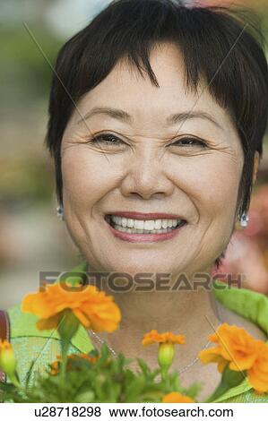 Stock Photo - Woman Holding Flowers outdoors, portrait, close up. Fotosearch