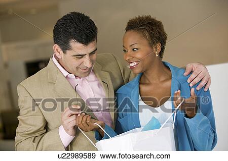Woman in store Showing Man Purchases in Shopping Bag, front view View Large Photo Image Stock Photo - Woman in store Showing Man Purchases in Shopping Bag, front view. Fotosearch