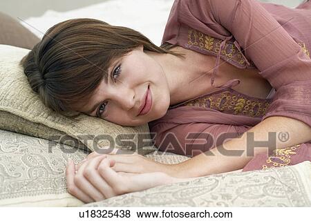 Stock Photo - Woman laying on pillows, portrait, elevated view. Fotosearch