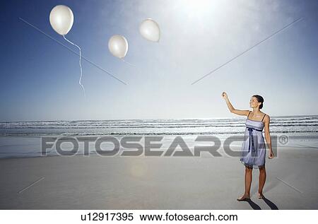 Woman letting balloons go on beach, elevated view View Large Photo Image Stock Photography - Woman letting balloons go on beach, elevated view. Fotosearch