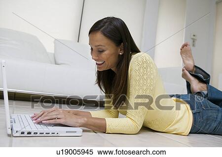 Woman lying on floor of living room Using Laptop, ground view View Large Photo Image Stock Photography - Woman lying on floor of living room Using Laptop, ground view. Fotosearch