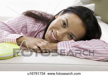 Picture - Woman Lying on sofa by Portable CD Player, portrait. Fotosearch