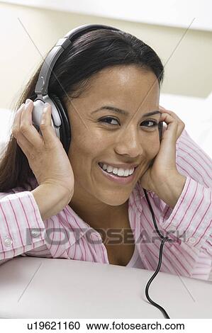 Woman lying on sofa Listening to Music on headphones, portrait View Large Photo Image Stock Image - Woman lying on sofa Listening to Music on headphones, portrait. Fotosearch