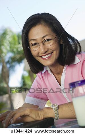 Picture - Woman sitting at backyard table Using Laptop, portrait. Fotosearch