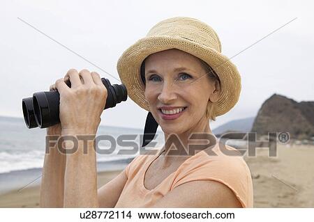 Woman using binoculars at beach, (portrait) View Large Photo Image Picture - Woman using binoculars at beach, (portrait). Fotosearch