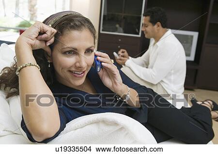 Picture - Woman Using Cell Phone on Sofa, close up. Fotosearch