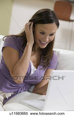 Woman Using Laptop on sofa in living room View Large Photo Image Stock Photography - Woman Using Laptop on sofa in living room. Fotosearch