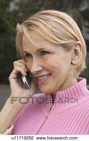 Stock Image - Woman using mobile phone, outdoors. Fotosearch