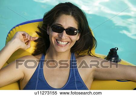 Woman wearing sunglasses, lying on inflatable raft in swimming pool, portrait. View Large Photo Image Stock Photography - Woman wearing sunglasses, lying on inflatable raft in swimming pool, portrait.. Fotosearch