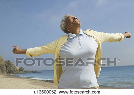 Stock Image - Woman with arms outstretched on beach. Fotosearch