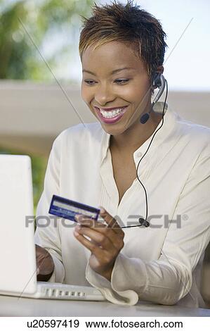 Stock Photo - Woman with laptop on patio Using Credit Card to make online purchase. Fotosearch