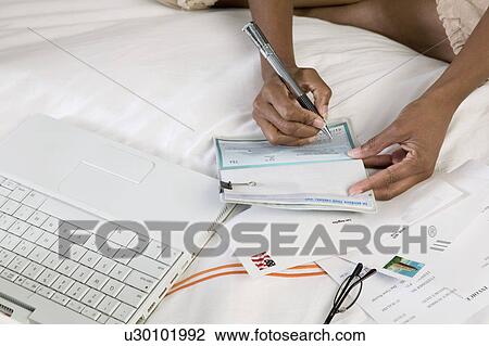 Woman Writing cheque on bed by laptop, close up of hands, high angle view View Large Photo Image Stock Image - Woman Writing cheque on bed by laptop, close up of hands, high angle view. Fotosearch