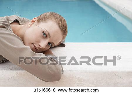 Stock Photo - Women lying at edge of swimming pool, portrait. Fotosearch