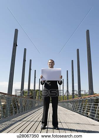 Young business man standing on bridge holding papers View Large Photo Image Stock Image - Young business man standing on bridge holding papers. Fotosearch