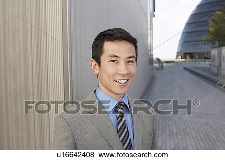 Young Businessman standing outside, smiling View Large Photo Image Stock Photo - Young Businessman standing outside, smiling. Fotosearch