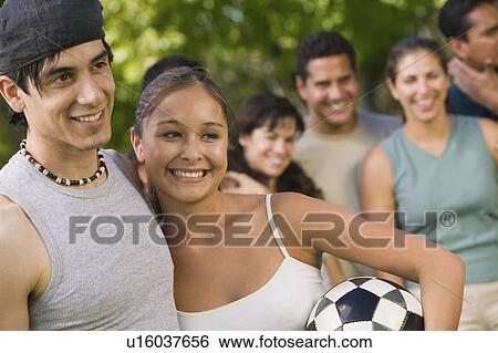 Stock Photograph - Young couple with family in background.. Fotosearch