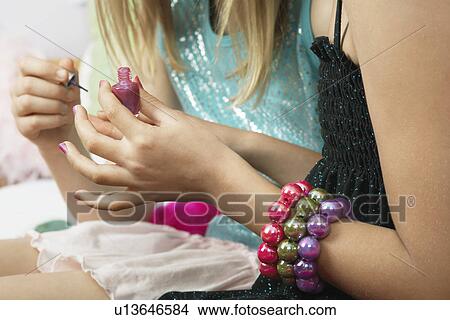 Young girl applying nail polish to friends fingernails, close-up View Large Photo Image Picture - Young girl applying nail polish to friends fingernails, close-up. Fotosearch