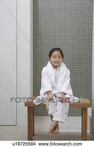 Picture - Young Girl wearing bathrobe, Sitting on Bench by Bathtub. Fotosearch