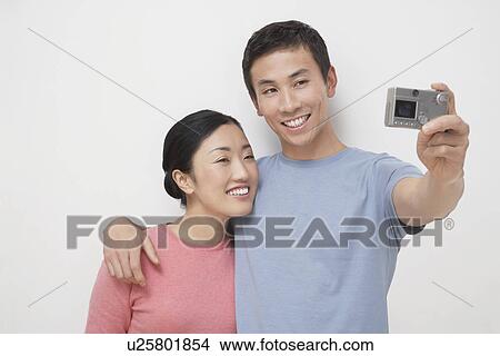 Young man, arm around girlfriend, taking picture of themselves View Large Photo Image Picture - Young man, arm around girlfriend, taking picture of themselves. Fotosearch