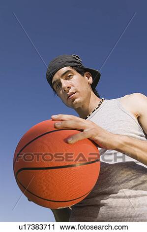 Stock Image - Young Man Holding Basketball, low angle view.. Fotosearch