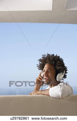Young man listening to music through headphones, portrait View Large Photo Image Stock Image - Young man listening to music through headphones, portrait. Fotosearch