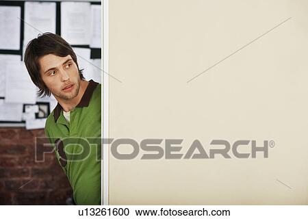 Stock Image - Young Man Looking Around Corner.. Fotosearch