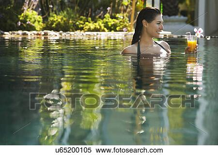 Young woman holding drink in natural swimming pool, portrait View Large Photo Image Stock Photography - Young woman holding drink in natural swimming pool, portrait. Fotosearch