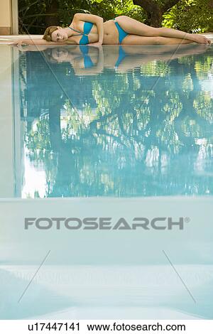 Young woman lying by swimming pool, portrait View Large Photo Image Stock Image - Young woman lying by swimming pool, portrait. Fotosearch