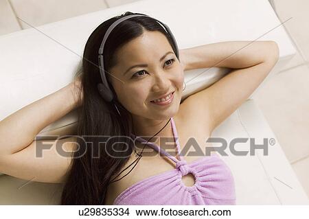 Picture - Young Woman lying on sofa Listening to Music, high angle view. Fotosearch