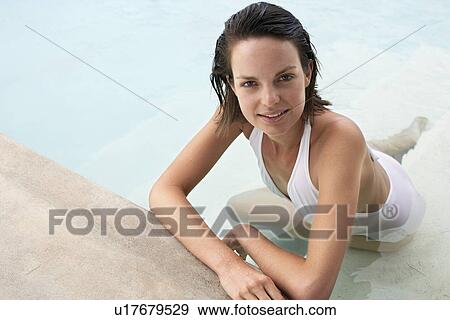 Stock Photo - Young woman relaxing in swimming pool, portrait, elevated view. Fotosearch