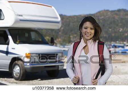 Young woman wearing backpack by RV at lake View Large Photo Image Stock Photo - Young woman wearing backpack by RV at lake. Fotosearch