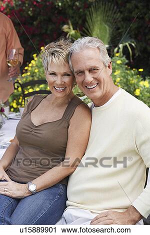 Affectionate middle aged couple sitting outdoors View Large Photo Image Stock Image - Affectionate middle aged couple sitting outdoors. Fotosearch