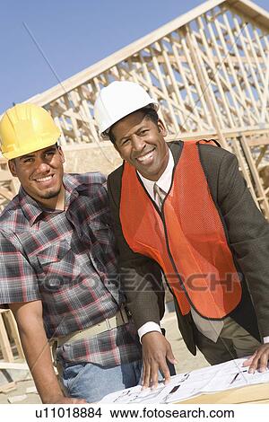Architect and construction worker leaning to table with blueprints View Large Photo Image Picture - Architect and construction worker leaning to table with blueprints. Fotosearch