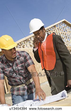 Architect and construction worker leaning to table with blueprints View Large Photo Image Picture - Architect and construction worker leaning to table with blueprints. Fotosearch