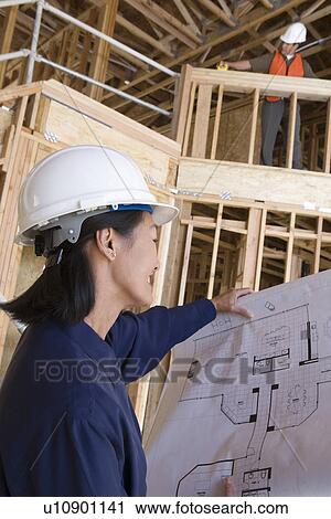 Stock Image - Architect and construction worker examining half constructed house. Fotosearch