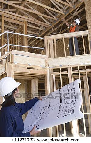 Architect and construction worker examining half constructed house View Large Photo Image Stock Image - Architect and construction worker examining half constructed house. Fotosearch