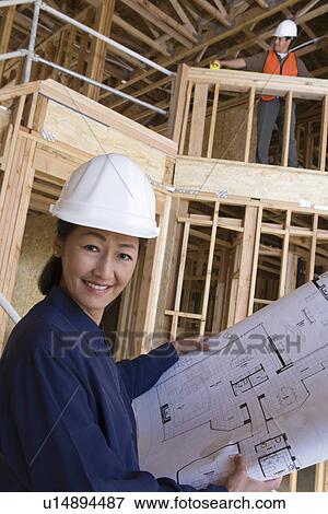 Stock Photo - Architect and construction worker examining half constructed house. Fotosearch