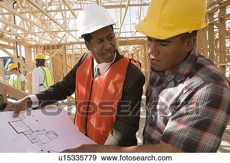 Stock Photo - Architect and construction worker looking at blueprints. Fotosearch