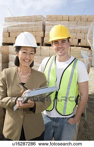 Architect and construction worker standing on construction site View Large Photo Image Stock Photograph - Architect and construction worker standing on construction site. Fotosearch