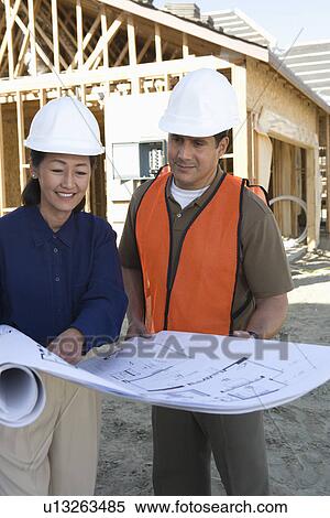 Architect and construction worker looking at blueprints on construction site View Large Photo Image Stock Photography - Architect and construction worker looking at blueprints on construction site. Fotosearch
