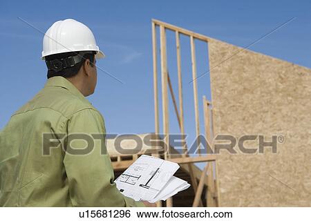 Architect holding blueprints on construction site View Large Photo Image Stock Photograph - Architect holding blueprints on construction site. Fotosearch