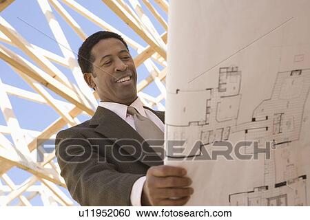 Stock Image - Architect looking at blueprints. Fotosearch