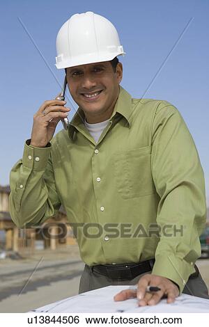 Stock Photograph - Architect talking on mobile phone over blueprints. Fotosearch