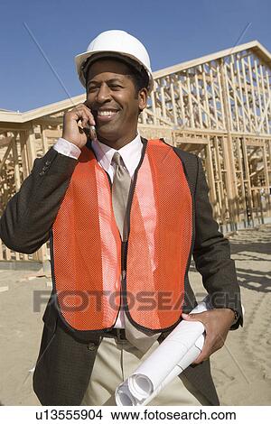 Architect talking on mobile phone holding blueprints View Large Photo Image Picture - Architect talking on mobile phone holding blueprints. Fotosearch