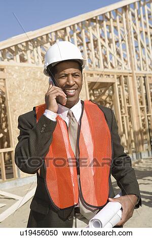 Architect talking on mobile phone holding blueprints View Large Photo Image Stock Image - Architect talking on mobile phone holding blueprints. Fotosearch