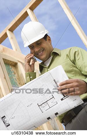 Stock Photo - Architect talking on mobile phone holding blueprints. Fotosearch