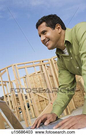 Stock Image - Architect using laptop on construction site. Fotosearch