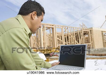 Architect using laptop on construction site View Large Photo Image Stock Photograph - Architect using laptop on construction site. Fotosearch
